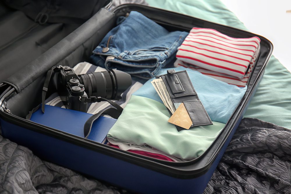 Open suitcase with packed things on bed for Europe travel essentials guide